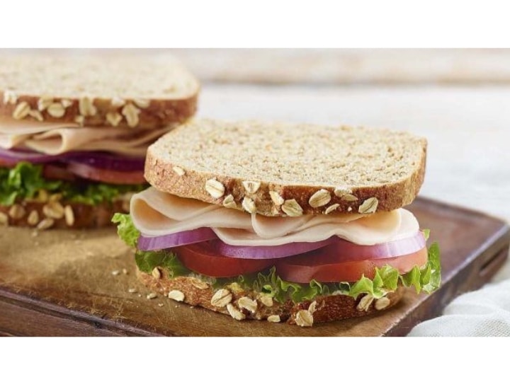 A turkey sandwich with lettuce, onion, and tomato.