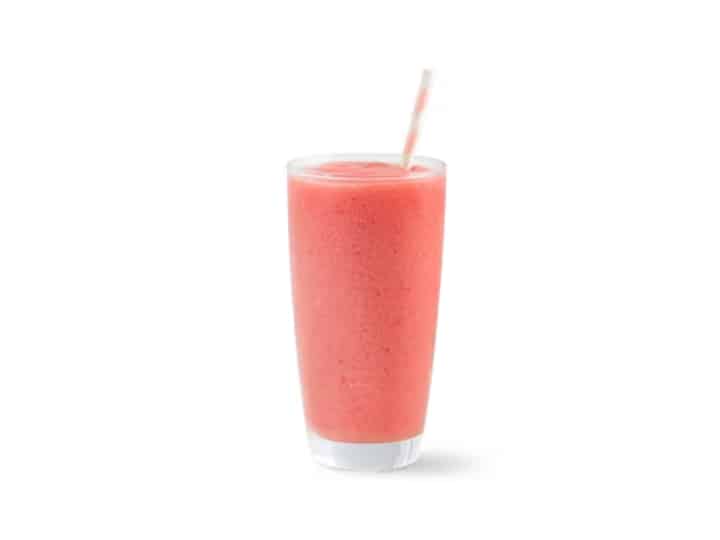 A pink smoothie in a glass cup.