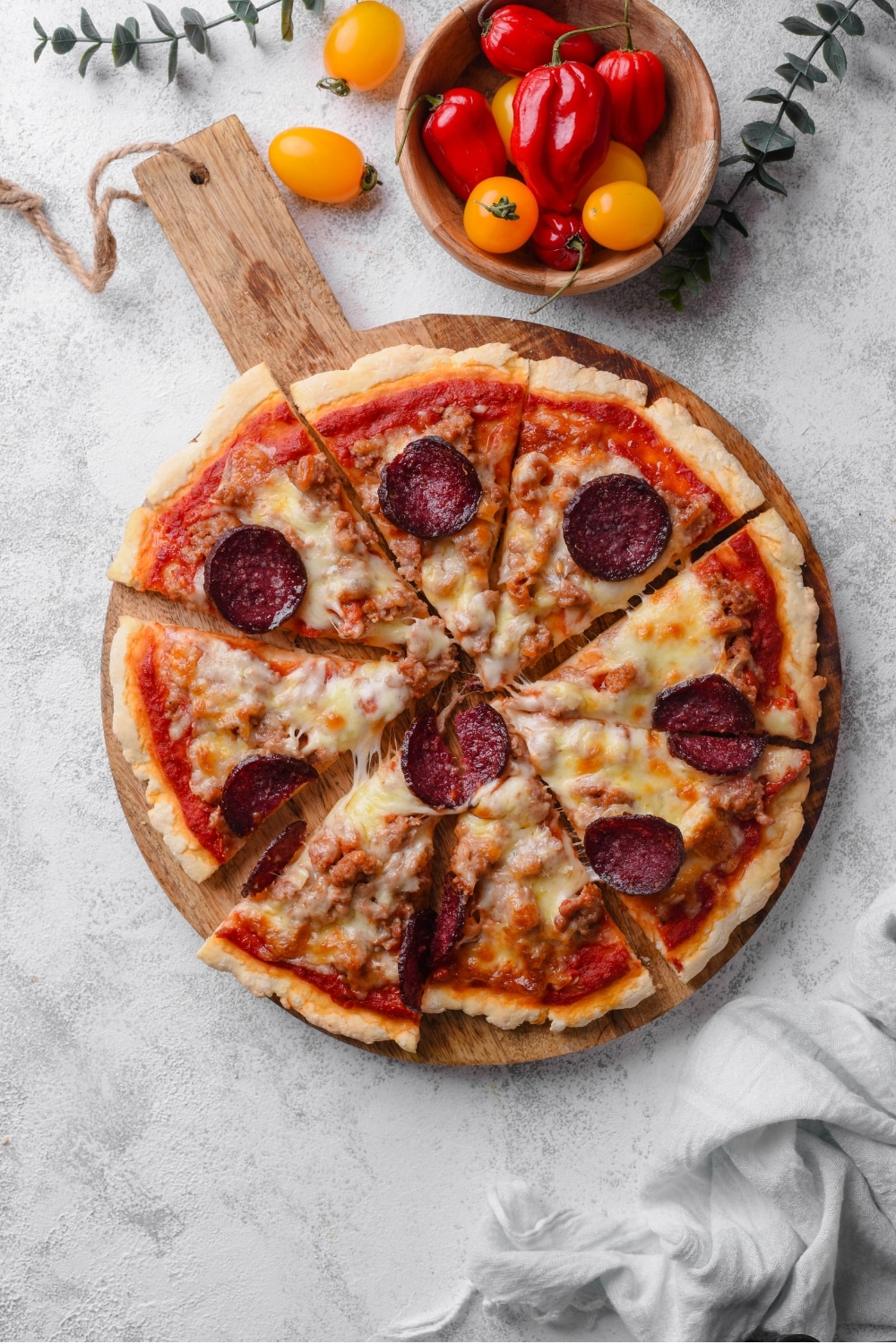 An overhead shot of a whole pizza sliced on a wooden server. The pizza is topped with cheese, pepperoni, and sausage.