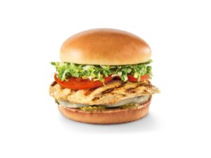 A grilled chicken sandwich with tomato, lettuce, and pickles.