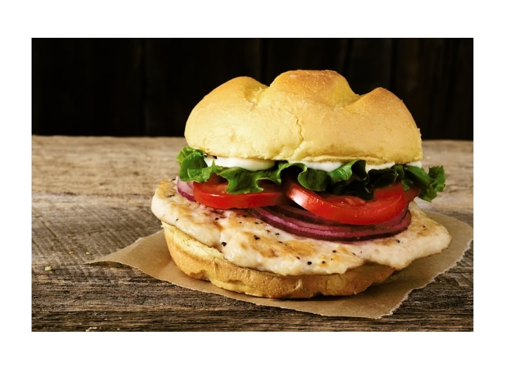 A grilled chicken sandwich on crusty bread with lettuce and tomato and mayo.