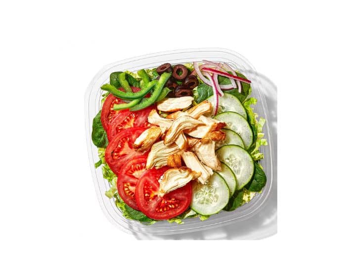 Rotisserie chicken, cucumber, olive, green bell pepper, and red onion on top of a salad.