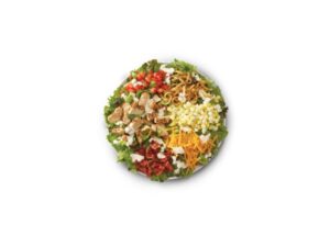 A cobb salad with chicken, cheese, egg, bacon and lettuce.