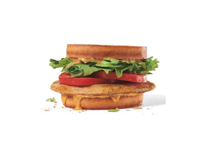 A grilled chicken sandwich with lettuce and tomato on a sourdough bun.