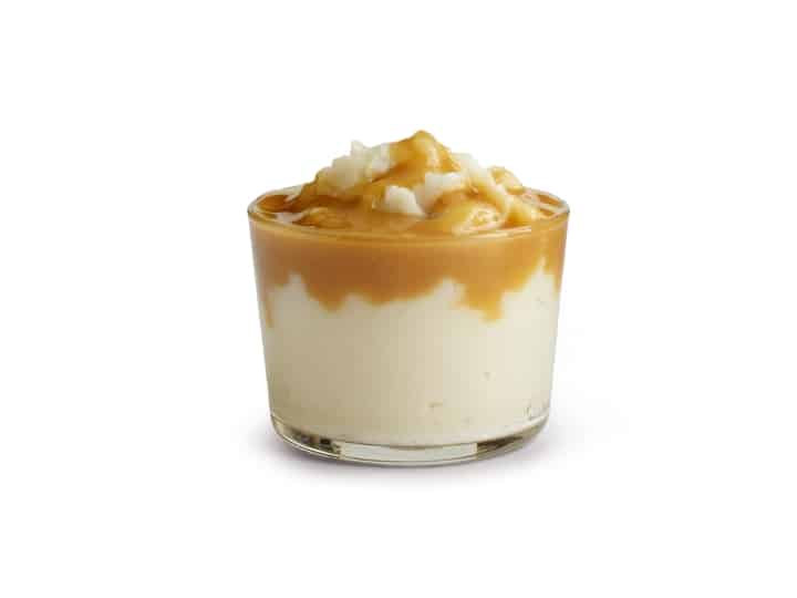 A glass cup of mashed potatoes with gravy.