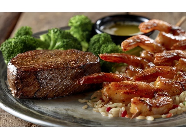 A piece of steak and a bunch of grilled shrimp.