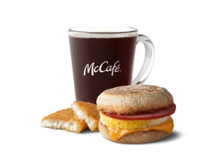 Canadian bacon egg and cheese sandwich a hash brown cut in half and a glass of coffee