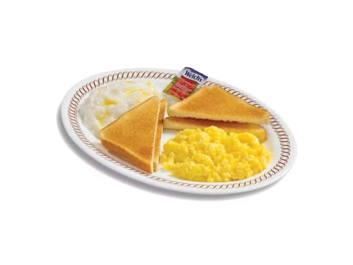 Scrambled eggs with two pieces of toast and grits on a white plate.