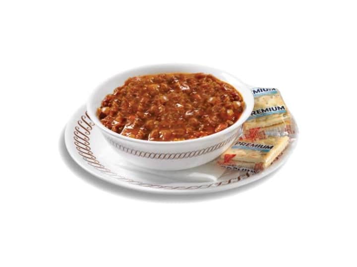 Chili in a white bowl on a white plate with cracker.