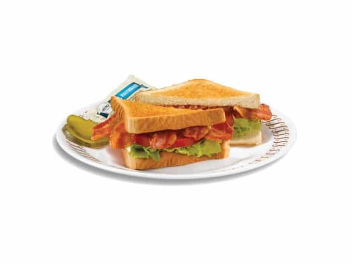 A sandwich with bacon, lettuce, and tomato on a white plate.