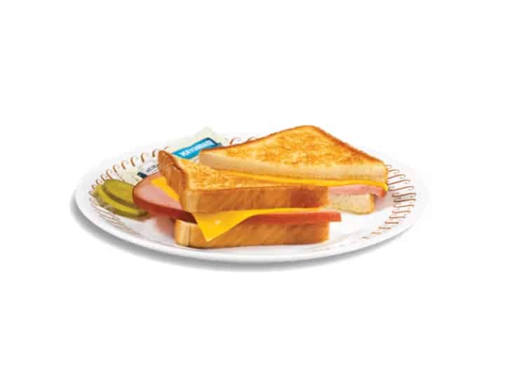A ham sandwich with cheese on a white plate.