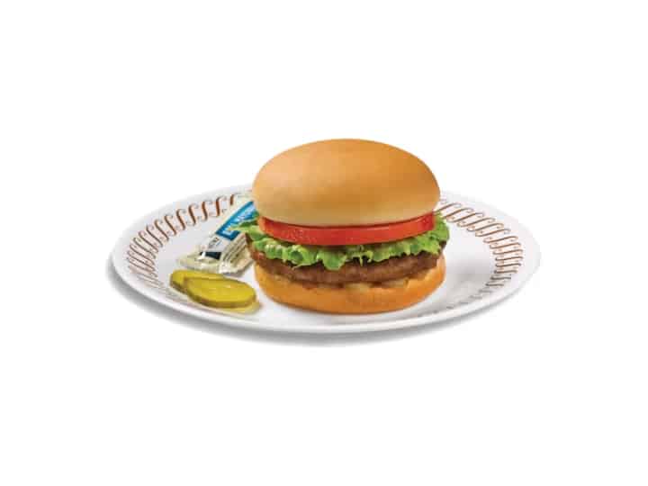 A hamburger with lettuce and tomato on a bun on a white plate.