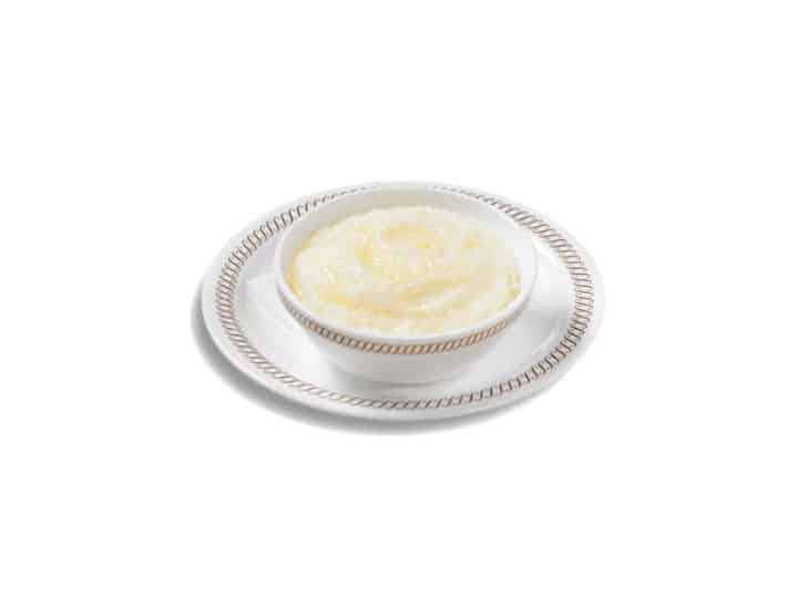 Grits in a white bowl on a white plate.