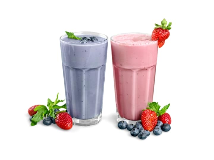 A blueberry smoothie in a glass and a strawberry smoothie in a glass.