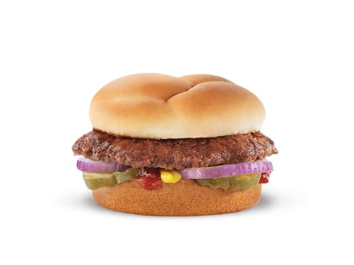 A hamburger with purple onion, pickles, ketchup and mustard,