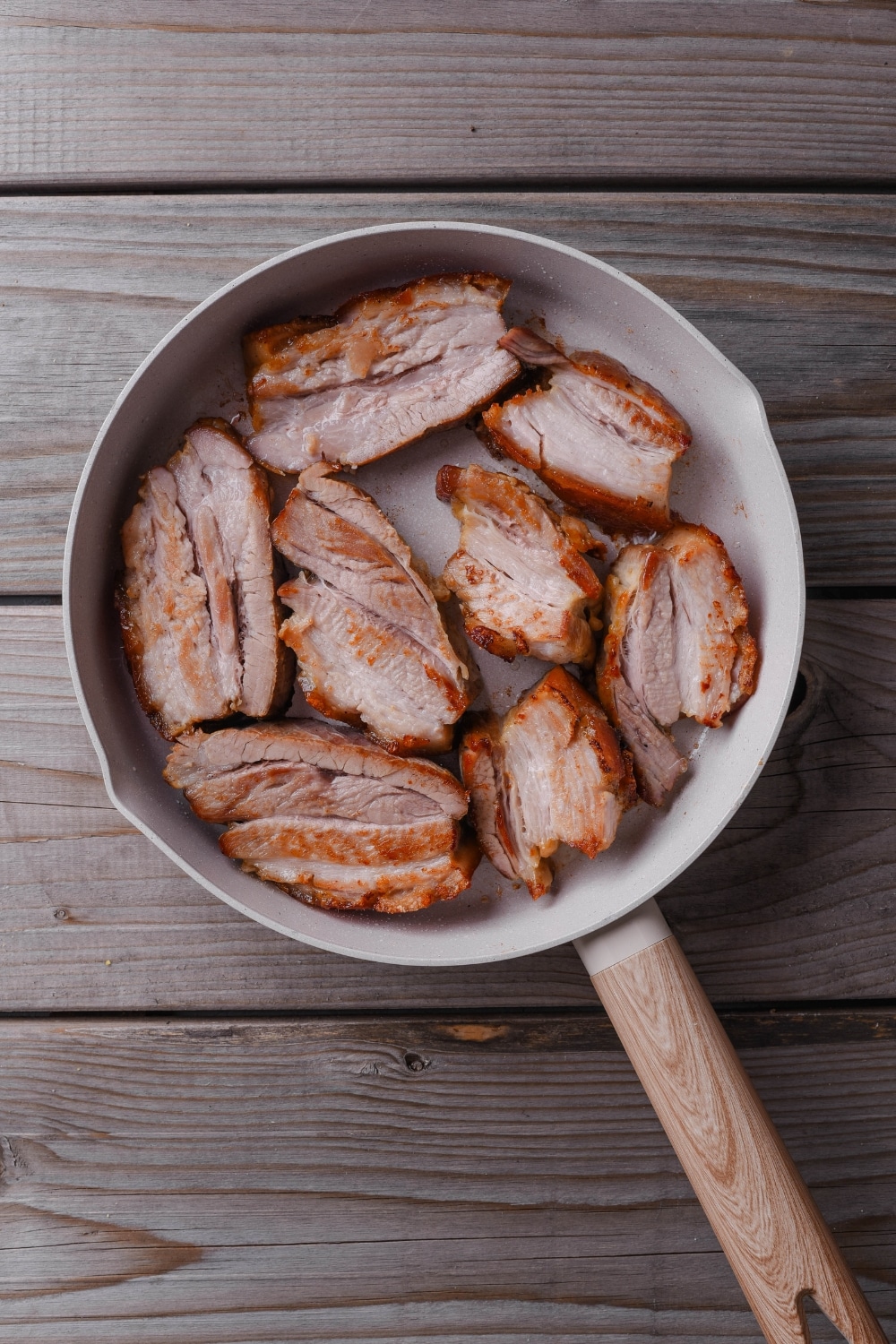 An overhead shot of sliced roasted pork belly in a ceramic pan.