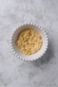An overhead shot of a white porcelain bowl filled with an egg salad mixture.