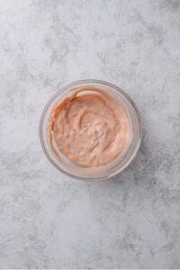 An overhead shot of a small glass bowl filled with a low calorie big mac sauce mixture.