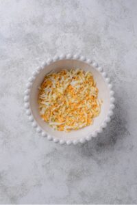 An overhead shot of a white porcelain bowl filled with chopped hard boiled egg.