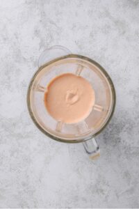 An overhead shot of a glass blender with blended low calorie big mac sauce.