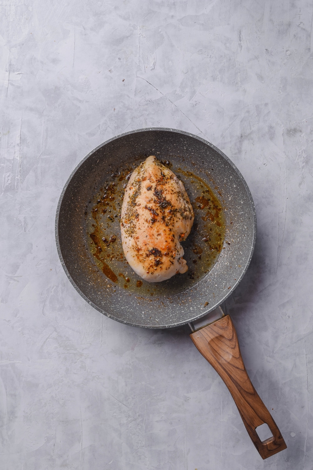 An overhead shot of a ceramic skillet with cooked chicken breast.