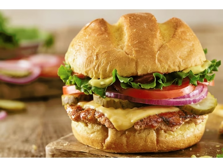 A turkey burger with lettuce, tomato, cheese, and onion.