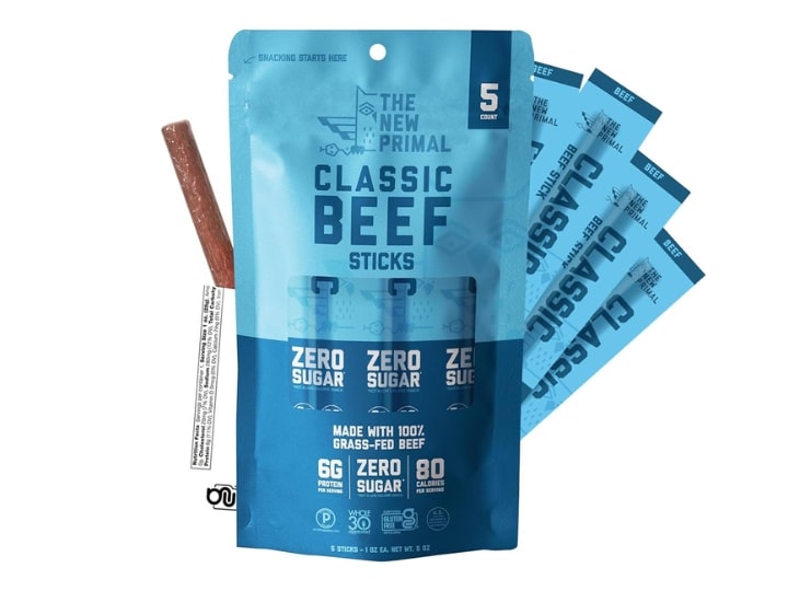 A bag of New Primal Beef sticks. There are sticks behind the bag and one stick is opened on the left hand side of the bag.