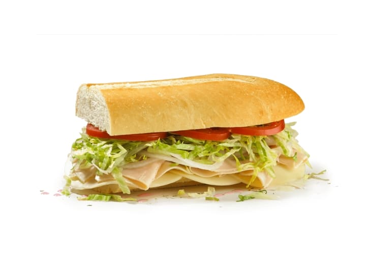 A half a sub with tomato, lettuce, turkey, and provolone.