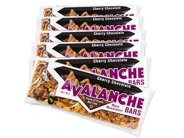 Several individual Avalanche cherry chocolate granola bars stacked in a line on a white background.