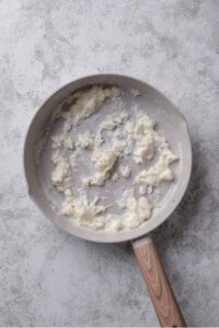 An overhead shot of a ceramic skillet with cooked egg whites on a marble countertop.