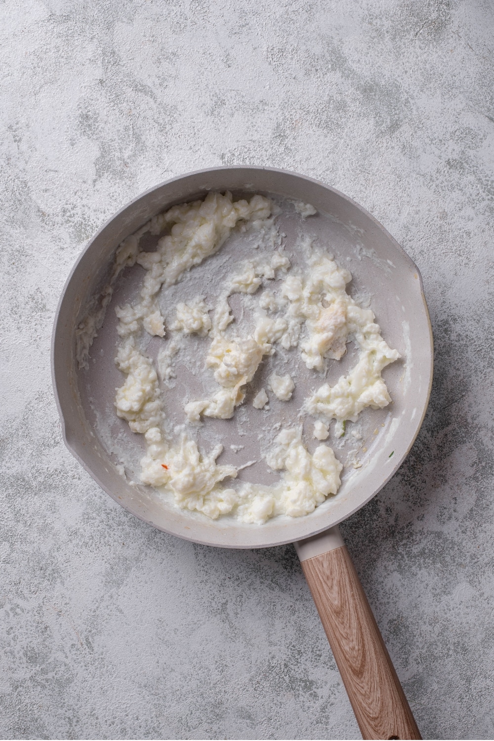 An overhead shot of a ceramic skillet with cooked egg whites on a marble countertop.