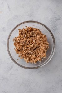 A clear bowl filled with unbaked granola.
