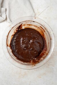 Overhead view of a clear bowl filled with chocolate cake batter.