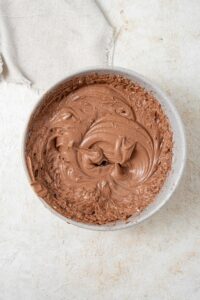 Overhead view of a grey bowl filled with chocolate frosting.