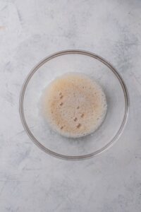 A clear bowl filled with frothy egg whites.