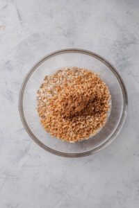 A clear bowl filled with brown rice cereal, oats, and cinnamon.