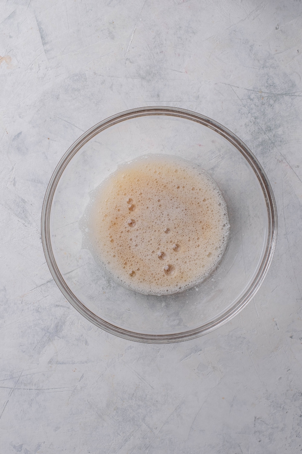 A clear bowl filled with frothy egg whites.