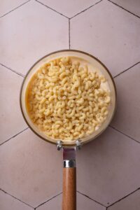 A pot filled with cheese sauce and macaroni noodles piled on top of the sauce.