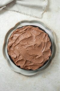 Overhead view of a chocolate cake covered in chocolate frosting on a serving plate.