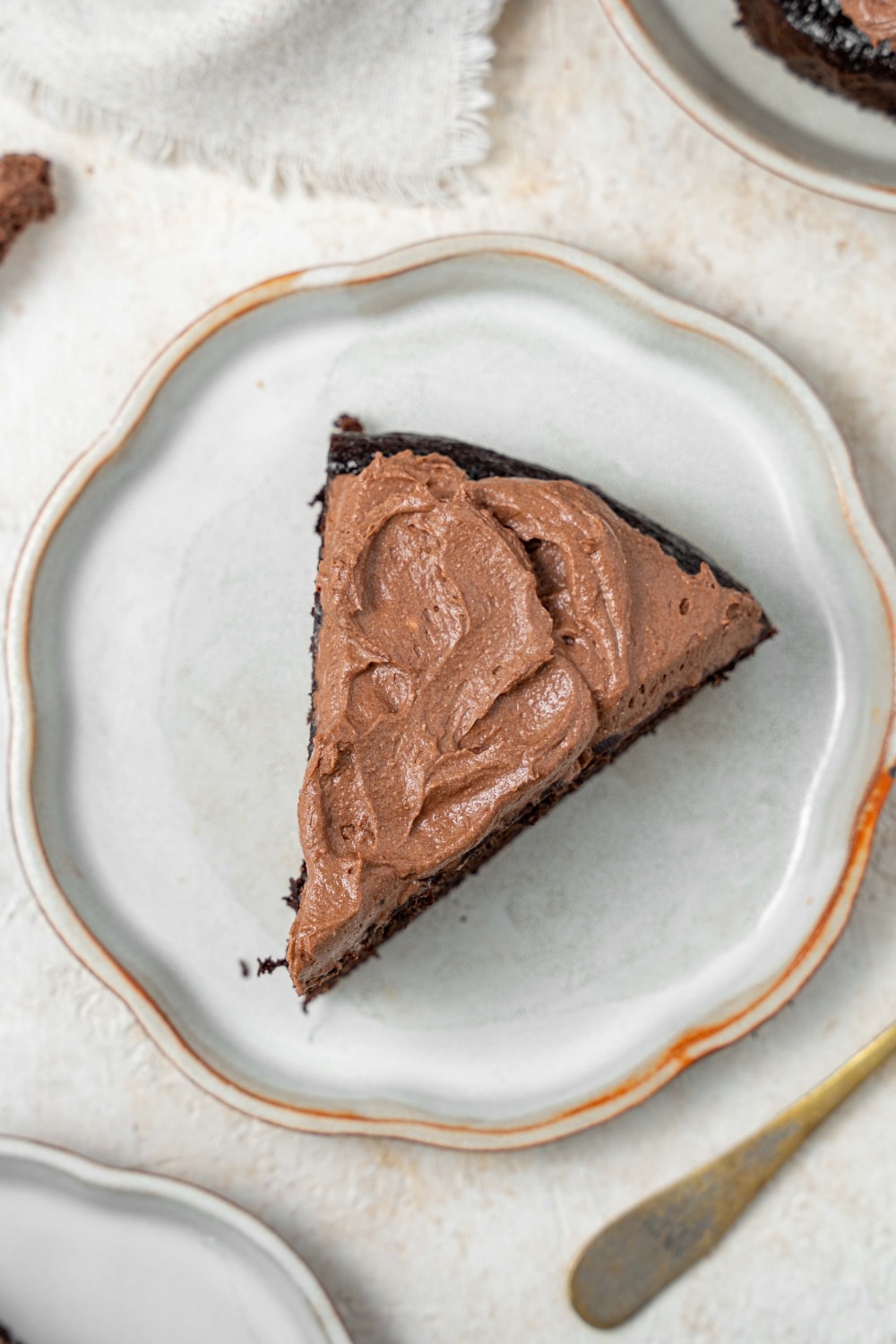 A slice of chocolate cake covered in chocolate frosting on a plate.