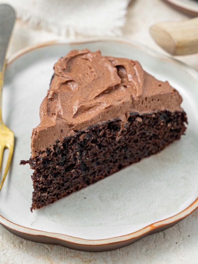 A slice of chocolate cake topped with chocolate frosting on a plate with a fork.