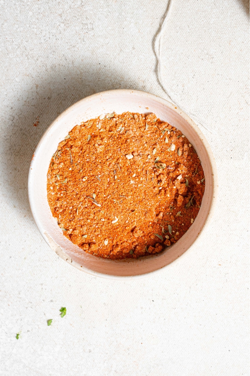 An overhead shot of a ceramic bowl filled with cajun seasoning to make blackened mahi mahi. The bowl is on a marble counter.