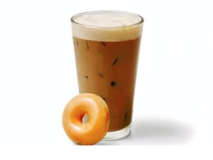 An image of an original iced glazed coffee from Krispy Kreme in a glass cup with a doughnut to the side on a white background.