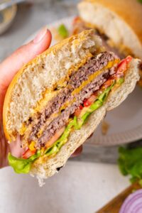 A closer look at the smash burger cross-section, layered with patties, veggies, cheese, and sauce.
