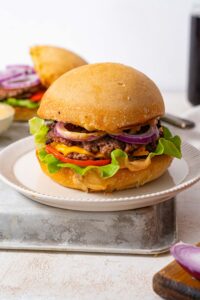 A fully stacked smash burger on a plate.