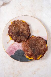 Seared smashed burger patties stacked into piles of two, with a slice of cheese in each stack.
