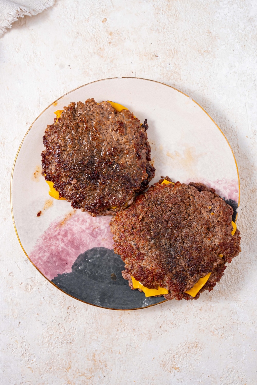 Seared smashed burger patties stacked into piles of two, with a slice of cheese in each stack.