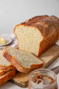 A sliced loaf of cottage cheese bread on a wooden cutting board.