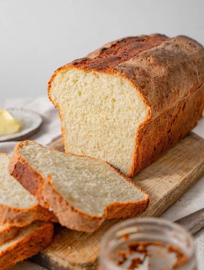 A sliced loaf of cottage cheese bread on a wooden cutting board.