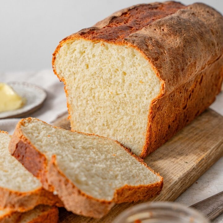A sliced loaf of cottage cheese bread on a wooden cutting board.